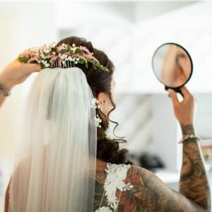 Braut mit Schleier schaut sich im Spiegel an